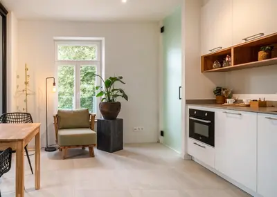 a kitchen with white cabinets and a table with a potted plant at Mavue kamer met terras in Mechelen