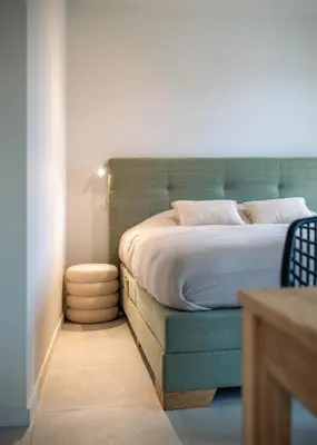 a bedroom with a large bed with a green headboard at Mavue kamer met terras in Mechelen