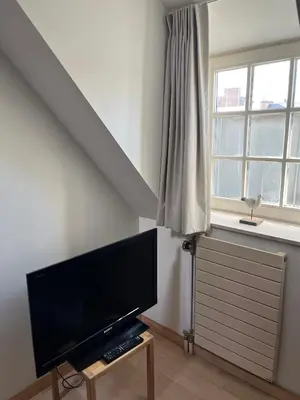 a living room with a flat screen tv and a window at Studio Tintin in Brussels