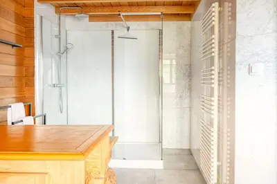 a glass shower door in a room with a desk at Cozy 4-Bedroom Chalet with Outdoor Spa in Zottegem in Zottegem