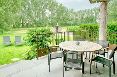 a patio with a table and chairs on a deck at Cozy 4-Bedroom Chalet with Outdoor Spa in Zottegem in Zottegem