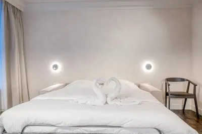 two swans sitting on top of a white bed at Chic 3P Retreat in Heart of Ghent in Ghent