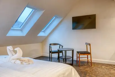 a bedroom with skylights and a bed and chairs at Charming Attic Studio in Ghent in Ghent
