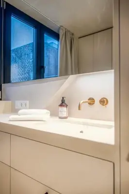 a white bathroom with a sink and a mirror at Charming Attic Studio in Ghent in Ghent