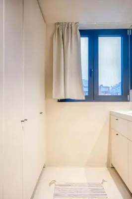 a white kitchen with a window and a rug at Charming Attic Studio in Ghent in Ghent