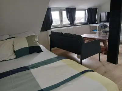 a bedroom with a bed and a chair and a table at Flat at Relegem in Asse