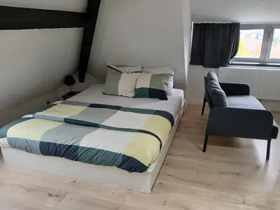 a bedroom with a bed and a chair and a window at Flat at Relegem in Asse