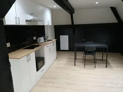 a kitchen with white cabinets and a table with a chair at Flat at Relegem in Asse