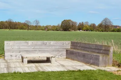 a wooden bench and a table in a field at Vakantiewoning de Huismus in Oud-Turnhout
