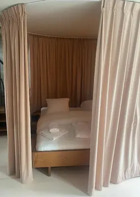 a bed with white sheets and pillows next to a curtain at Studio Conda in Antwerp