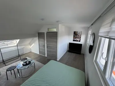 a small room with a green bed and a table at Qozyroom in Brussels
