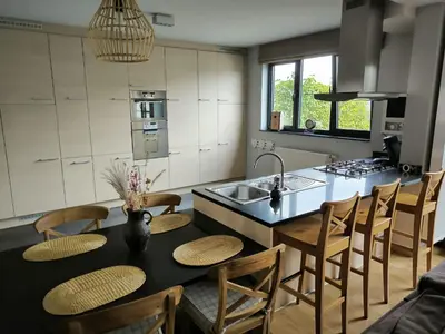 a kitchen with a table with chairs and a sink at Vakantiewoning De Zilverberk in Geraardsbergen