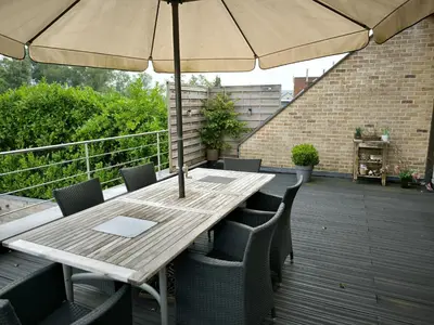 a wooden table with chairs and an umbrella on a deck at Vakantiewoning De Zilverberk in Geraardsbergen