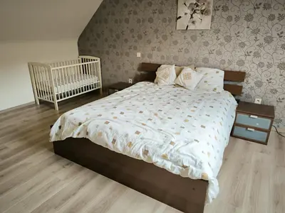 a bedroom with a large bed and a crib at Vakantiewoning De Zilverberk in Geraardsbergen