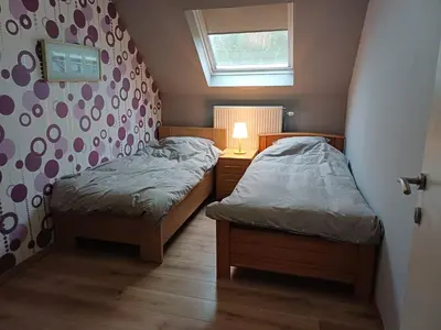 two beds in a small bedroom with a window at Vakantiewoning De Zilverberk in Geraardsbergen