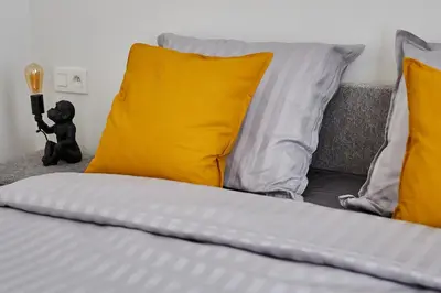 a bed with yellow pillows and a teddy bear on it at Urban Chic Apartment in the Heart of Mechelen in Mechelen