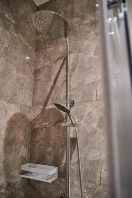 a shower in a bathroom with a stone wall at Urban Chic Apartment in the Heart of Mechelen in Mechelen