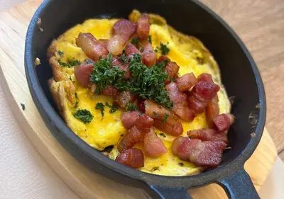 a pan filled with omelet with bacon and cheese at Hotel Hallensis in Halle