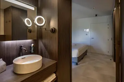 a bathroom with a sink and a bedroom with a bed at Hotel Hallensis in Halle