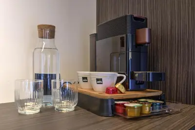 a table with glasses and a bottle and a coffee maker at Hotel Hallensis in Halle