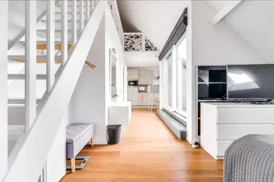 a bedroom with white walls and a bed and a staircase at Espace moderne pouvant accueillir 3 personnes in Vilvoorde