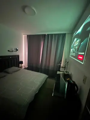 a bedroom with a bed and a tv and curtains at Sweetroom in Brussels