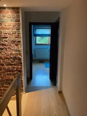 an empty hallway with a brick wall and a window at Nice flat near Brussels in Dilbeek