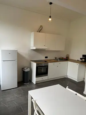 a kitchen with white cabinets and a table in it at Bruxelles midi flat in Brussels