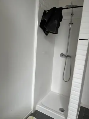a white bathroom with a shower and a black towel at Bruxelles midi flat in Brussels