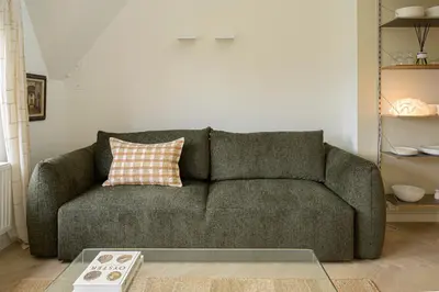a living room with a green couch with a pillow at SHWAY - The Printing Press in Antwerp