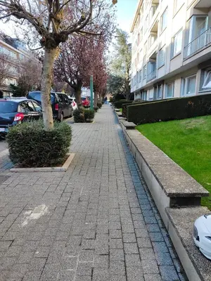 a brick sidewalk next to a building with cars parked at Flat moderne et lumineux in Brussels