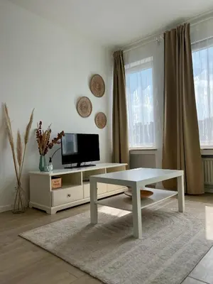 a white living room with a table and a tv at Flat moderne et lumineux in Brussels