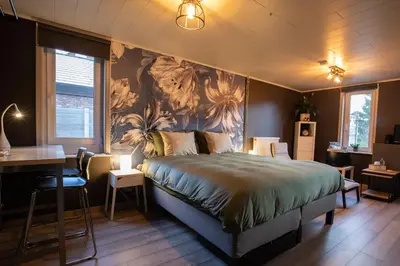 a bedroom with a bed and a table and a desk at B&B De Oude Berg in Mol
