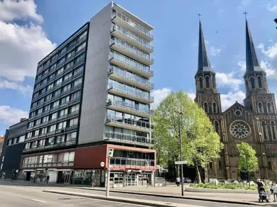 a tall building in front of a church at Central Apartment with City Park View and Terrace in Antwerp