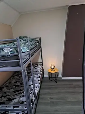 a room with two bunk beds and a table at Gezellige Rijwoning met tuin in Werkstede