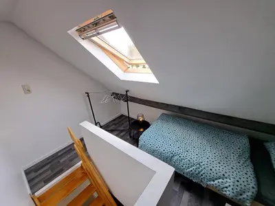 a loft bedroom with a bed and a skylight at Gezellige Rijwoning met tuin in Werkstede
