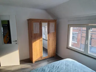 a bedroom with a wooden cabinet and a window at Gezellige Rijwoning met tuin in Werkstede