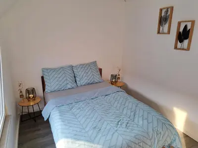 a bedroom with a bed with blue sheets and two tables at Gezellige Rijwoning met tuin in Werkstede