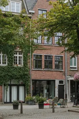 a brick building with tables and chairs in front of it at SHWAY - The Proof Reader in Antwerp