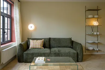 a living room with a green couch and a glass table at SHWAY - The Proof Reader in Antwerp