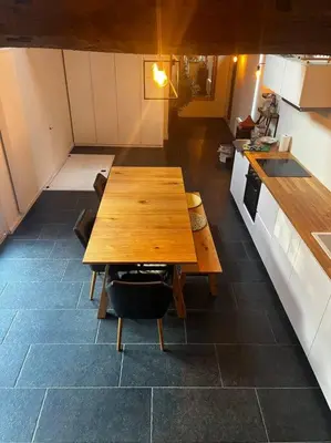 a kitchen with a wooden table in the middle of a room at Melkhuisje in Dendermonde