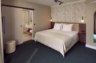 a bedroom with a large white bed and a bathroom at Van der Valk Hotel Park Lane Antwerpen in Antwerp