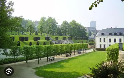 a park with a row of trees and a building at Surplombant louisa in Brussels