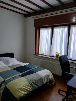 a bedroom with a bed and a chair and a window at Assenaar in Asse