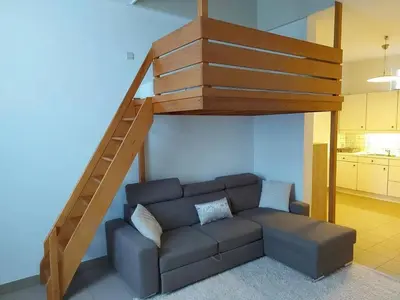 a living room with a couch and a staircase at Charming Apartment in Haren, Brussels - 40 sqm of Comfort in Brussels