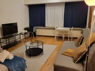 a living room with a couch and a flat screen tv at Prime Nest Cozy Studio EU Quarter in Brussels