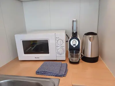 a kitchen counter with a microwave and a bottle of wine at Prime Nest Cozy Studio EU Quarter in Brussels