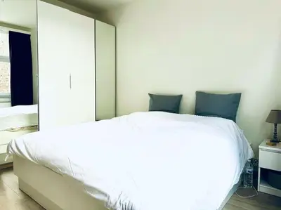 a bedroom with a white bed with a large mirror at Magnifique appartement spacieux in Brussels