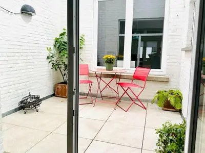 a patio with red chairs and a table on a patio at Magnifique appartement spacieux in Brussels