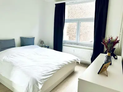 a bedroom with a white bed and a window at Magnifique appartement spacieux in Brussels
